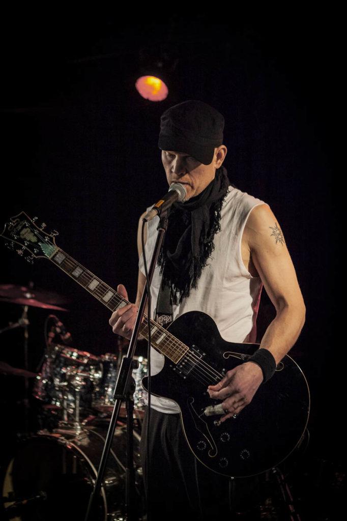 Kuvassa artisti SPK Toivonen lavalla, soittamassa kitaraa ja laulamassa