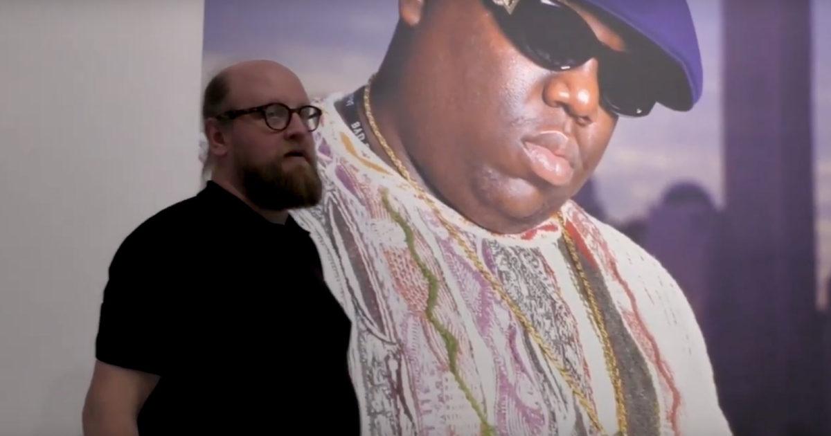 Kuraattori Jean Ramsey seisoo Chi Modun valokuvan edessä. Valtavassa valokuvassa on hiphop legenda Biggie.