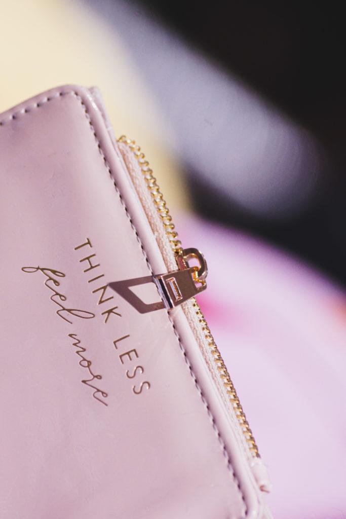 Lähikuva pinkistä lompakosta, jossa teksti: "Think less , feel more."