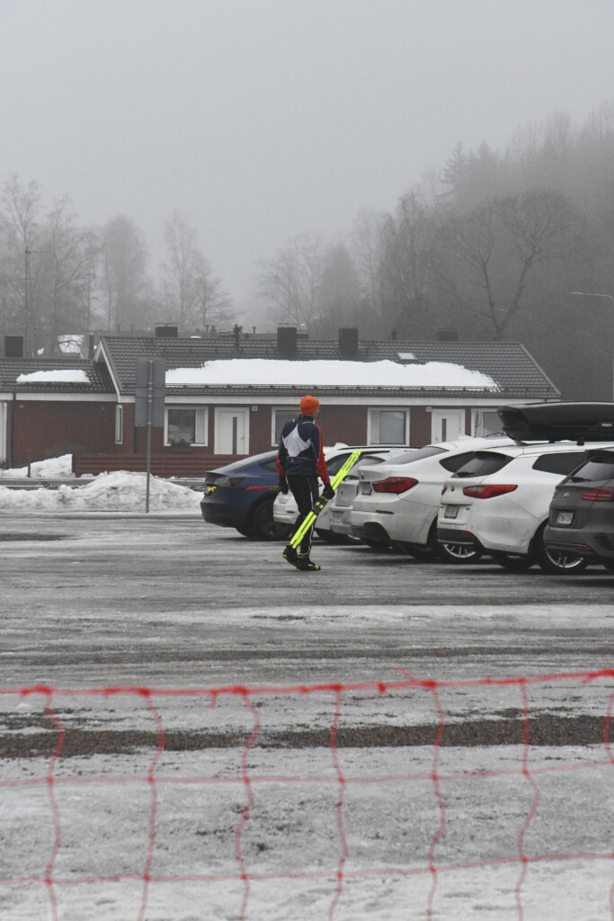 Hiihtäjä sulaneella parkkipaikalla.